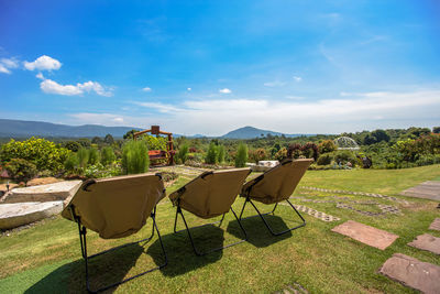 Chairs and table against trees on landscape against sky