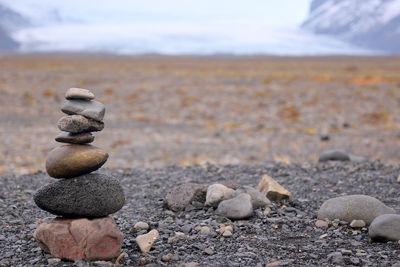 Stack of pebbles on sand at beach against sky