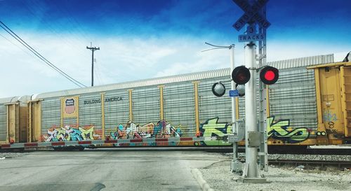 Road sign by railroad tracks against sky