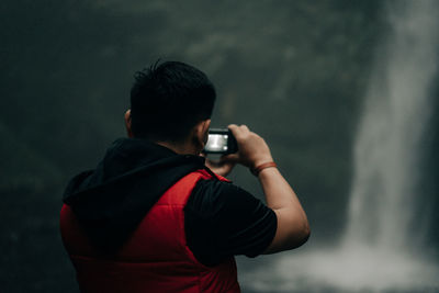 Side view of man photographing against wall