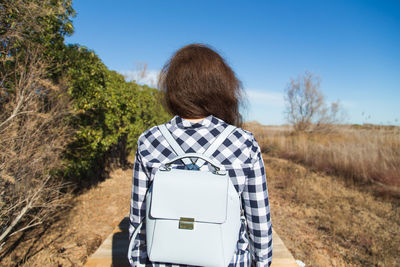 Rear view of woman standing on field against clear sky