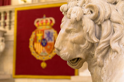 Statue of lion on coat of arms of spanish monarch on red board