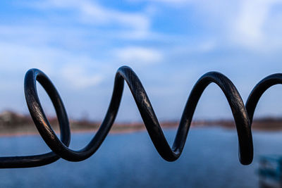 Close-up of metal fence against sky