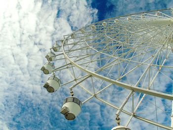 Low angle view of ferris wheel against cloudy sky