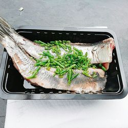 High angle view of fish with vegetables in container on table