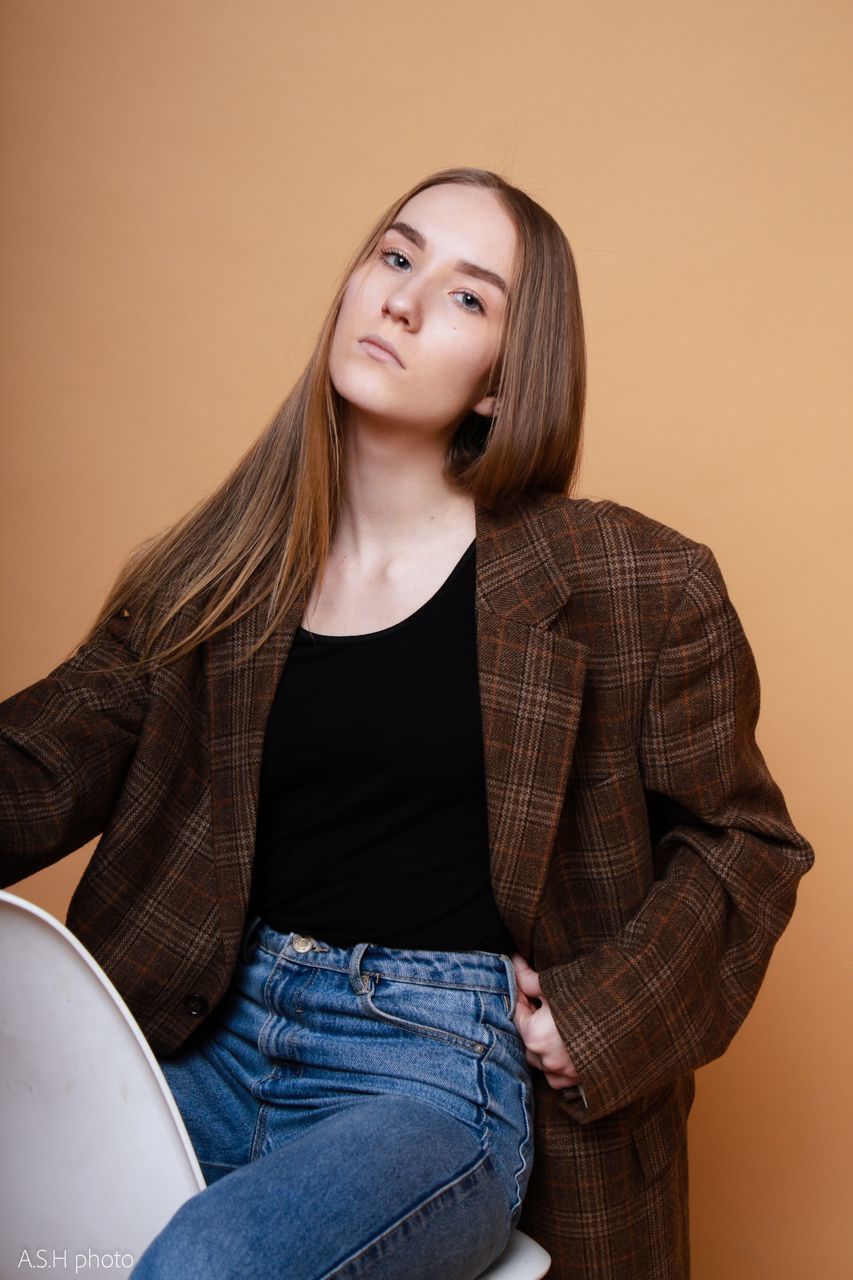 PORTRAIT OF A WOMAN SITTING AGAINST WALL