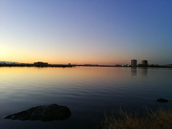 Scenic view of lake against clear sky during sunset