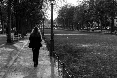 Rear view of woman walking on footpath