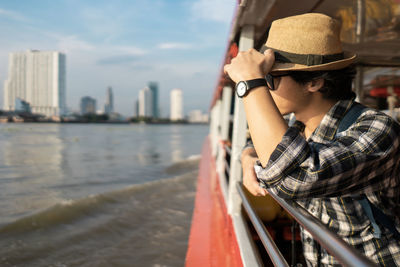 Tourist wearing hat standing in boat on river