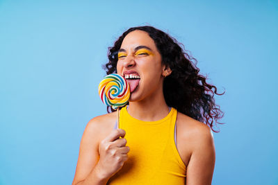 Portrait of smiling young woman blowing bubbles against blue background