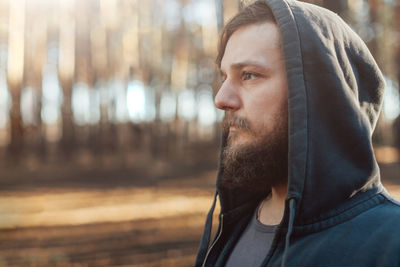 Bearded man in hooded jacket looking away