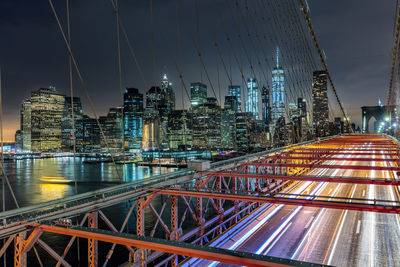 Illuminated bridge and buildings against sky at night