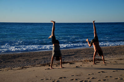 Rear view of young sportmen at beach