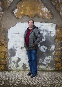 A man stands by an old brick wall