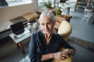Smiling businesswoman sitting on chair at coffee shop