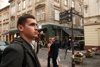 Side view of young man standing on street in city