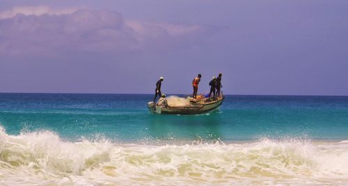 People in sea against sky