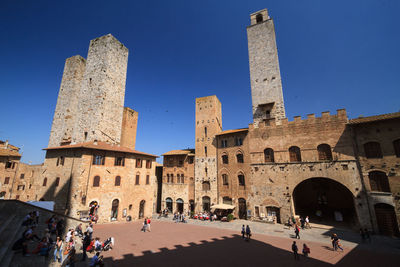 Group of people in front of built structure against blue sky