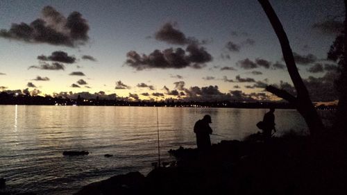 Silhouette of people at lakeshore