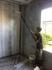 Man working with arms raised standing against wall