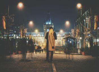 Man standing on illuminated street at night