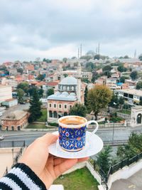 Woman holding coffee cup and buildings in city