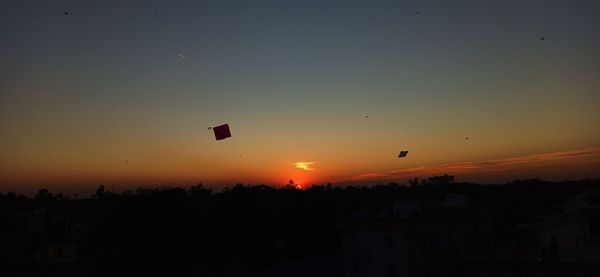 Silhouette of helicopter flying against sky during sunset