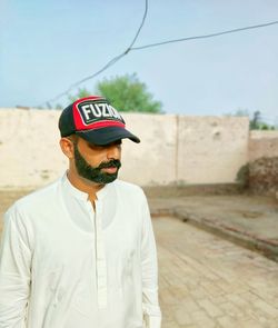 Young man wearing hat standing against sky