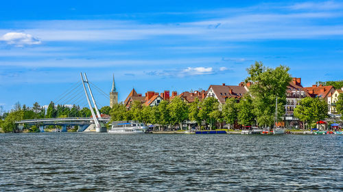 Scenic view of river by buildings against blue sky