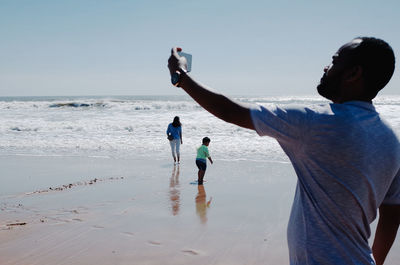 Rear view of people on beach against sky