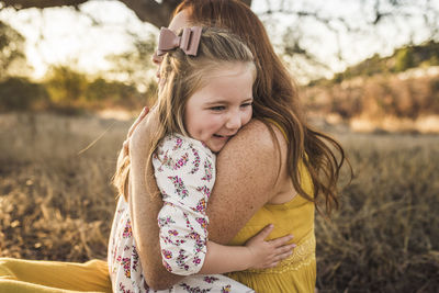 Close up of young girl embraced by mother in california field