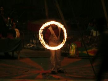 Midsection of man standing by illuminated lamp at night