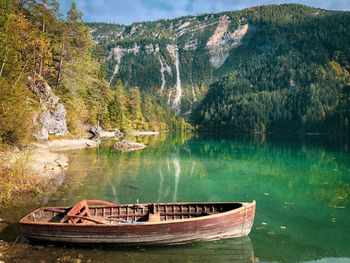 Boat moored by lake against mountain