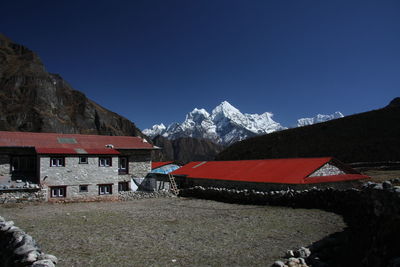 Built structure on snowcapped himalayan mountain against clear blue sky