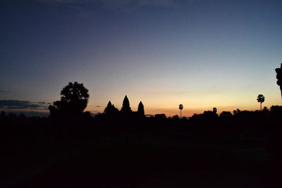 Silhouette trees and buildings against sky during sunset