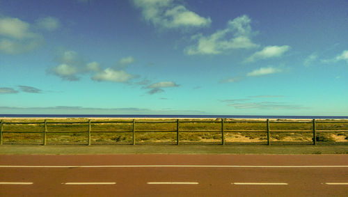 Road amidst field against sky