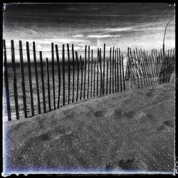 Wooden posts on beach against sky