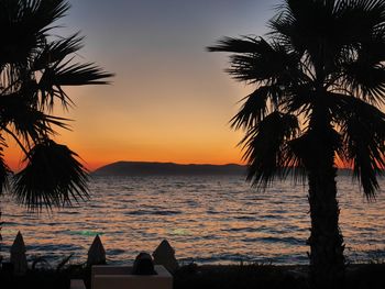 Silhouette palm trees on beach against sky during sunset