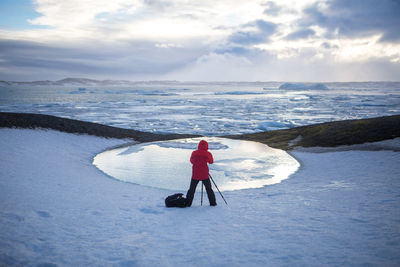 Rear view of person photographing glaciers on jokulsarlon lake