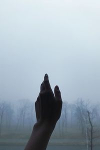 Cropped hand of person against sky