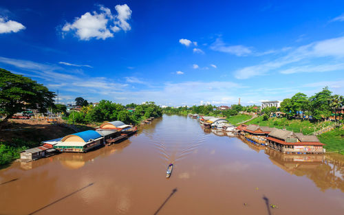 Scenic view of canal amidst trees and buildings against sky