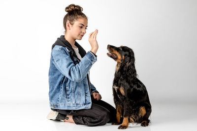 Young woman with dog sitting against white background