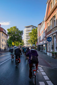 People riding bicycle on road amidst buildings in city
