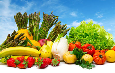 Various fruits and vegetables on table against blue sky