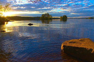 Rocks in sea against sky during sunset