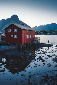 House by lake against sky during winter