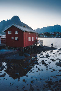 House by lake against sky during winter