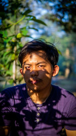 Portrait of young man standing amidst plants outdoors