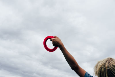 Low angle view of hand holding umbrella against sky