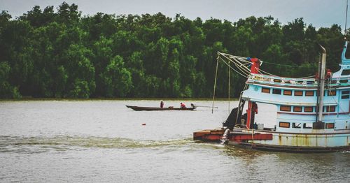 People on boat by river against sky